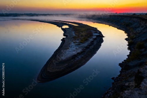 Sunset over a winding river with mist rising from the water surface