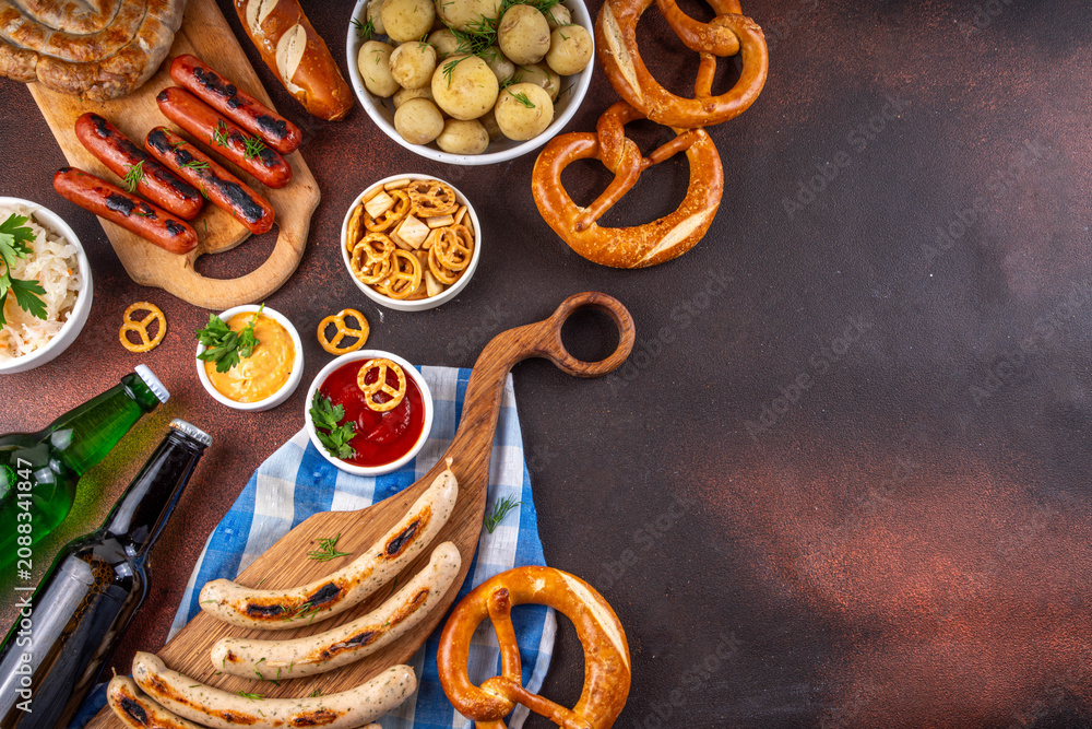 Fototapeta premium Oktoberfest picnic and barbecue food, bavarian party menu, bavarian sausages, pretzels, potato, sauerkraut, beer bottles, with picnic basket, checkered napkin tablecloth, Oktoberfest festive ribbon