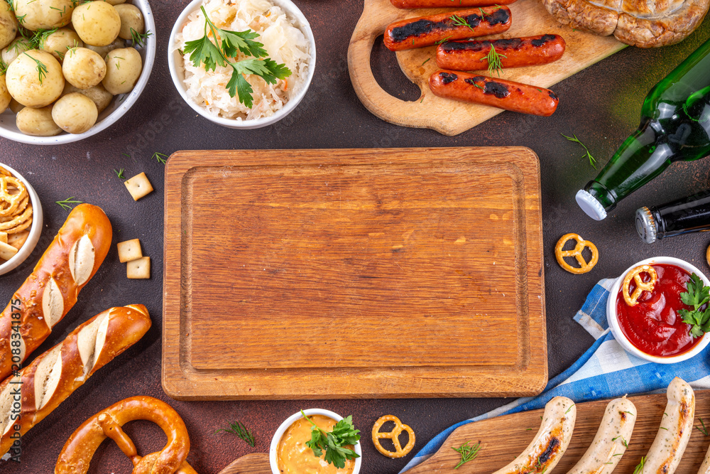 Fototapeta premium Oktoberfest picnic and barbecue food, bavarian party menu, bavarian sausages, pretzels, potato, sauerkraut, beer bottles, with picnic basket, checkered napkin tablecloth, Oktoberfest festive ribbon
