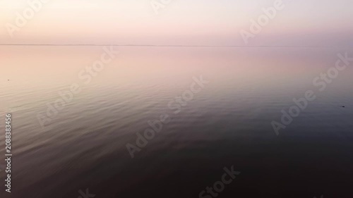 Ascending forward drone clip onto the Curonian Lagoon during sunset, in background Curonian Spit, Lithuania.
