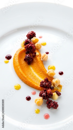 Creative fine dining dessert with smooth orange puree and berry topping