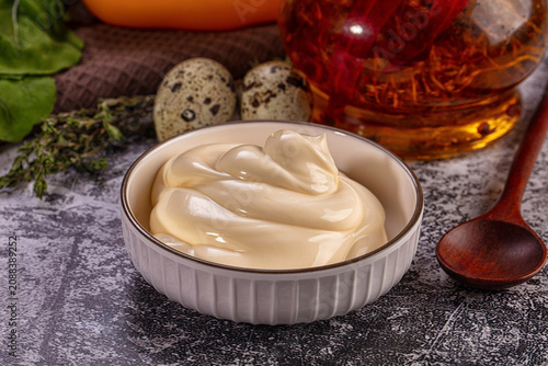 Bild auf Leinwand Creamy mayonnaise in white bowl with quail eggs and herbs on textured surface