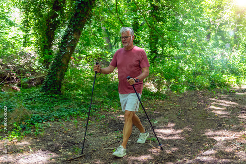 фотографія Senior man enjoying Nordic walking through a forest trail to improve cardiovascular fitness, balance, endurance, mobility, and support an active healthy lifestyle