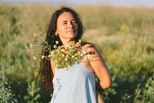 Woman with chamomile bouquet in summer field