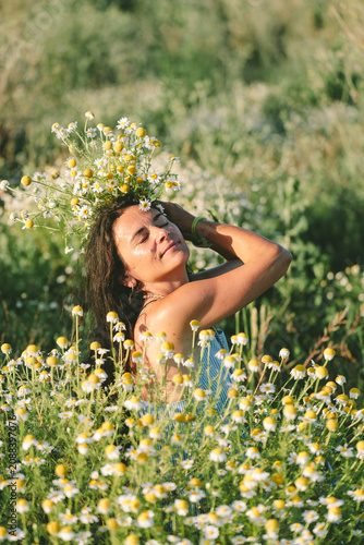 Woman with chamomile flower crown in meadow