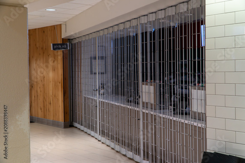 Fotografie Closed Food Service Counter with Metal Security Gate and 'Pick Up' Sign in an Em