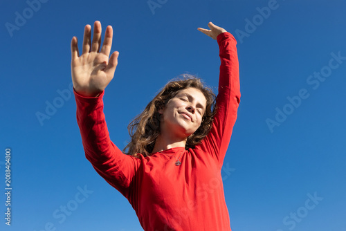dynamic shot of a young woman dancing dreamily in the sunlight under a cloudless blue sky. Energy, freedom, joy, and a call to action. copy space. A love for life, dreams, and positive mindset.