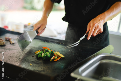 Obraz na plátně Chef stir frying fresh vegetables on hibachi grill