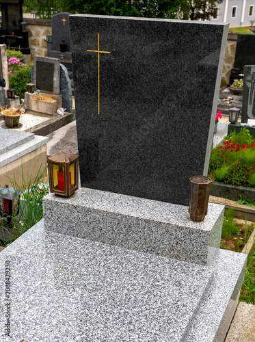 New grave with an unmarked headstone and granite grave cover, lantern, and vase in a village cemetery in Austria