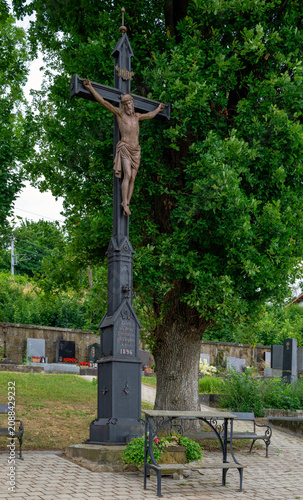 Statue of Christ on a large iron cross dating from 1896, in a small local cemetery in Austria