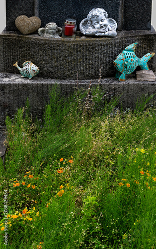 Lush, sprawling wildflowers on a grave with old ceramic grave decorations in Austria;
