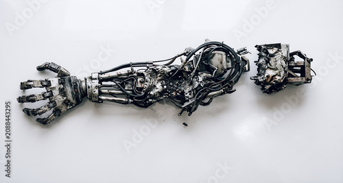 Inquadratura di braccio robotico umanoide gravemente danneggiato posato su una superficie bianca, primo piano con vista da sopra