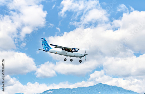 Single engine ultralight plane flying in the blue sky with white clouds