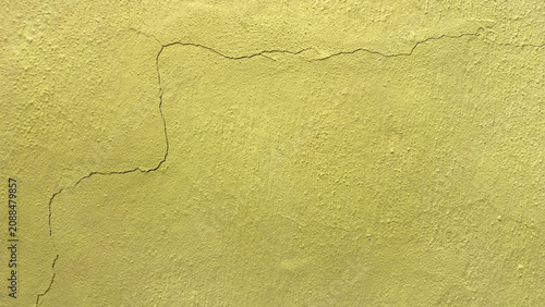 Foto Background featuring the texture of a yellow-painted concrete wall cracked after