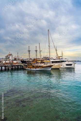 Picturesque harbor in Latchi featuring anchored yachts, sailing boats surrounded by turquoise sea. Mediterranean destination, tourism, relaxation and waterfront lifestyle concept.