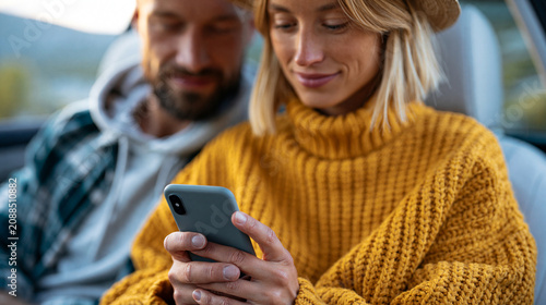 Faceless young couple using phone on road trip together checking social media, travel lifestyle concept, automotive photography, blurred outdoor background, with copy space
