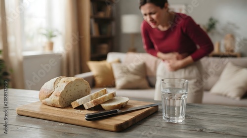 Woman experiencing stomach discomfort with bread and water on table