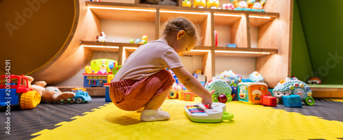 Fotografía Toddler playing with colorful musical toy piano in a bright playroom filled with
