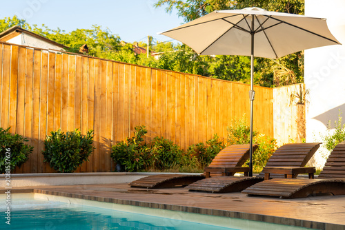 Foto Backyard poolside with wooden sun loungers and umbrella