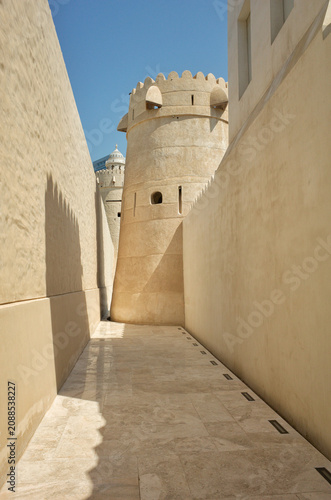 Narrow passage with beige walls leading to the historic tower of Qasr Al Hosn under bright sunlight in Abu Dhabi