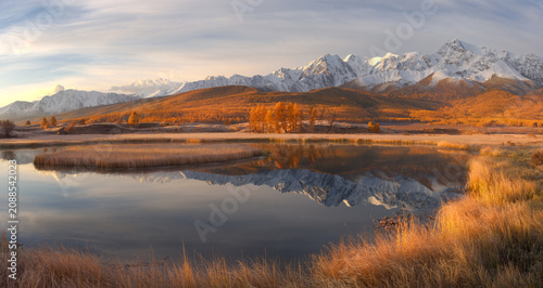 Amazing Autumn Mountain Landscape. Reflection Of Snowy Peaks And Thick Clouds On Still Water.