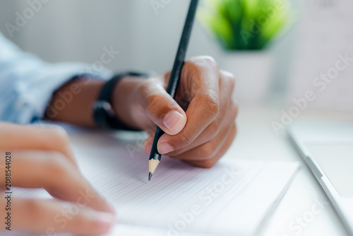 Obraz na płótnie a person hand writing with black pencil on lined notebook paper, taking notes, creative writing, document signing, education and deep focus concept