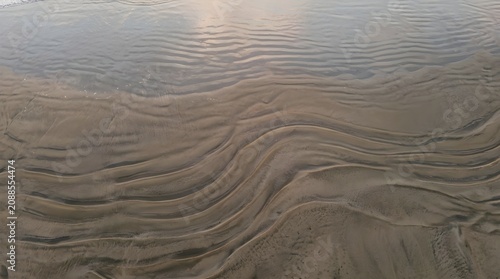 Ocean tide receding leaving textured sand patterns on a peaceful beach shore