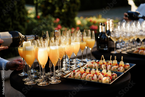 Canvas Print Waiter pouring mimosas into flute glasses at a wedding party with gourmet shrimp