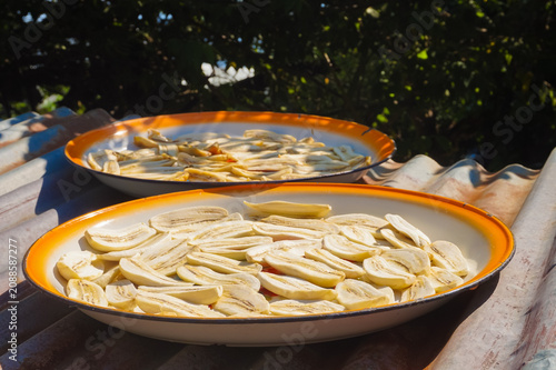 Quadro em tela Sunlit plates hold sliced bananas