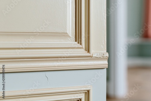 Detailed wood architrave and panel molding in an old home featuring cream and pale blue paint for architectural restoration and interior design