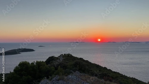Sunset over the sea viewed from a cliff on an island in Croatia during the evening hours with small islands in the background