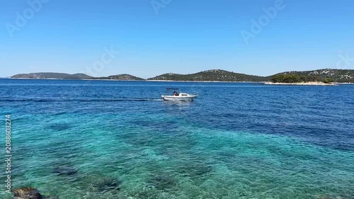 Boat sails across clear water near islands under bright sky in Croatia during sunny day