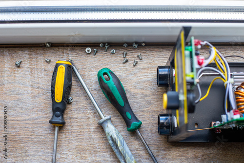 Tools and internal components of a disassembled welding inverter on a wooden surface. electronics repair, diy workshop, technical maintenance.