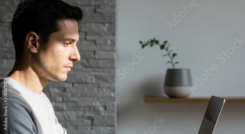 Man Concentrates On Laptop Screen In A Modern Minimalist Home Setting