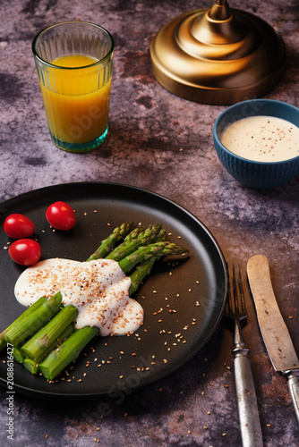 Foto Gourmet healthy breakfast with cooked asparagus, white sauce, orange juice and vintage cutlery