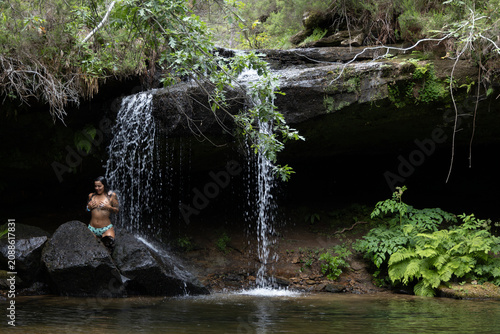 Bild auf Leinwand Mujer joven disfrutando de una cascada en un exuberante bosque tropical