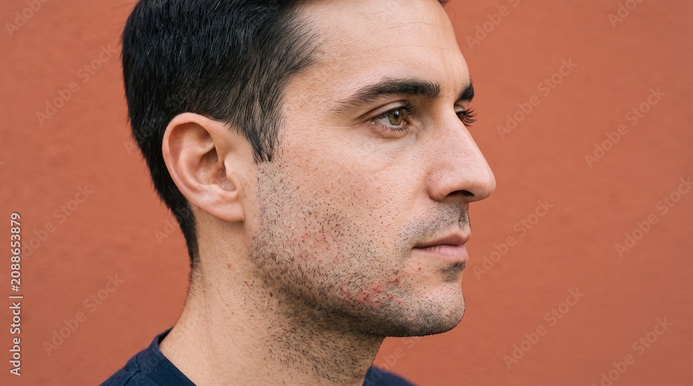 Fototapeta premium Close up profile of a man with acne on his face and stubble
