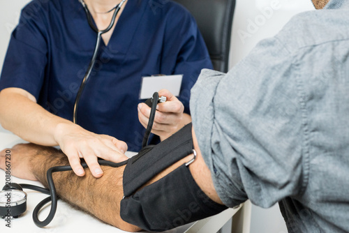 Tableau sur toile Healthcare professional using a manual sphygmomanometer and stethoscope to listen to the pulse and measure systolic and diastolic pressure of a patient