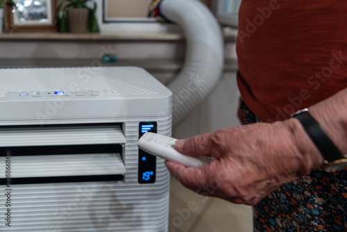 Senior controlling portable air conditioner with remote control for indoor climate comfort