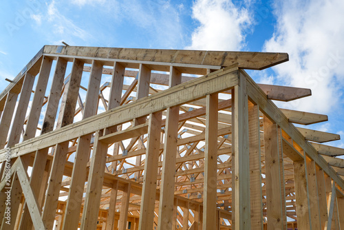 Timber Frame House Structure with Roof Trusses Under Construction Against Blue Sky on Sunny Summer Day