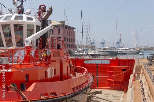 Cuadro en lienzo Red tugboat located out of the water in a dry dock in the port of Genoa