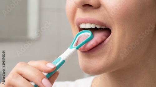 A woman performs tongue scraping as part of her daily dental care routine.