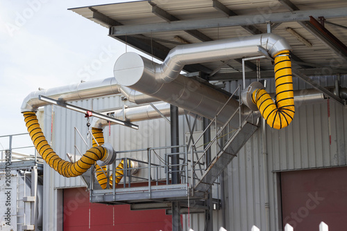Foto Industrial ventilation system with large metallic ducts and yellow flexible hose