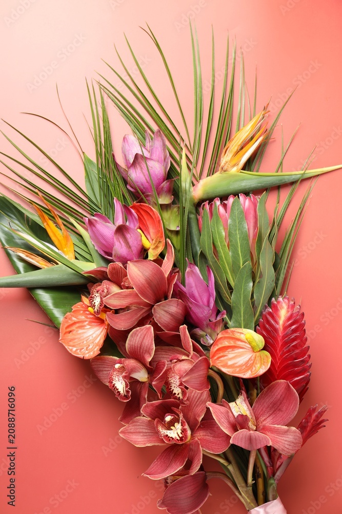 Fototapeta premium Bouquet of beautiful tropical flowers on red background, top view
