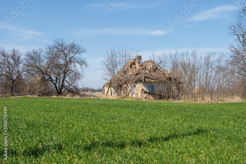 : Abandoned rural house beside a green agricultural field