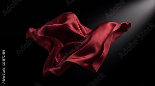 Elegant red silk fabric floating in motion against a black background with dramatic lighting