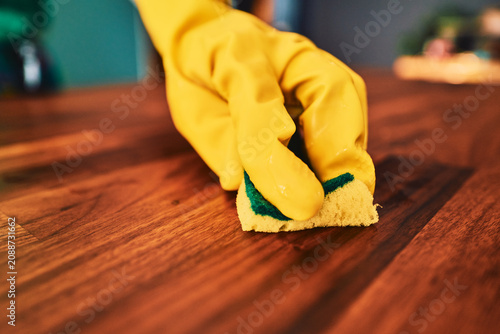 Cleaning a wooden surface with a sponge in rubber gloves