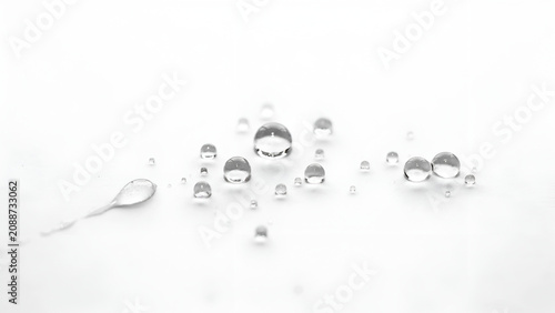 Macro of clear water droplets scattered on a white surface