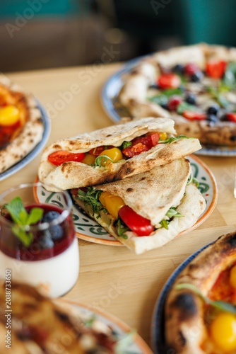 Flatbread Sandwich with Vegetables on Restaurant Table
Italian Piadina Sandwich Served with Pizza and Dessert
Casual Outdoor Lunch with Flatbread Sandwich and Pizza
