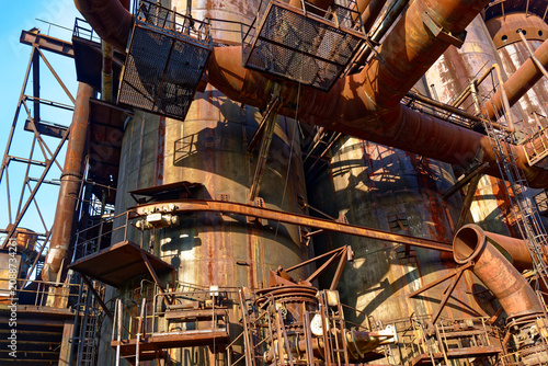 Rusty industrial blast furnace with pipes and catwalks